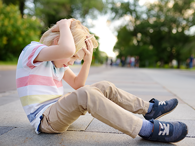 a girl and a boy holding a house cutout sitting in the grass on a