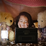 Little girl using tablet computer/tablet with teddy bears in fort