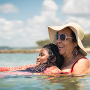 mother holding teenaged daughter while floating in a lake