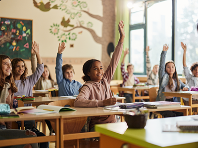 children raising their hands in a classroom