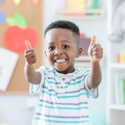 Little boy giving thumbs up in school room