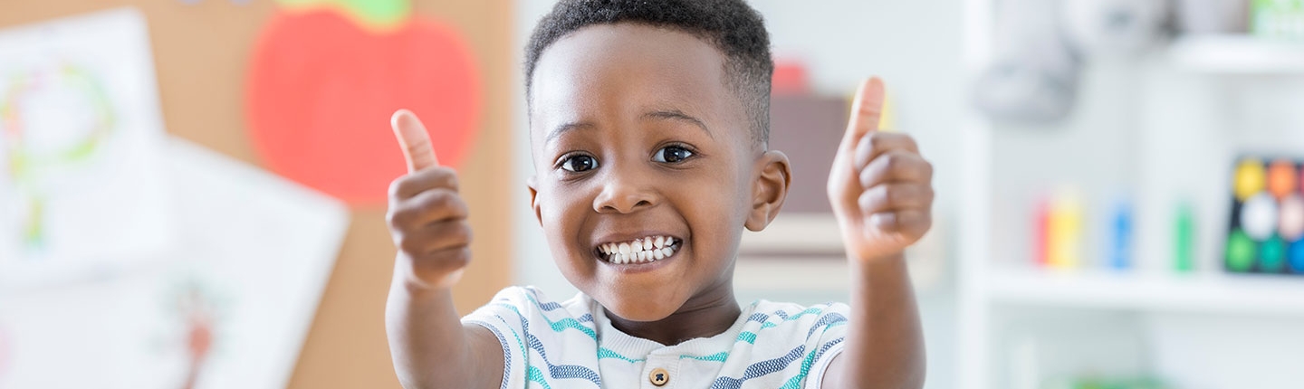 Little boy giving thumbs up in school room