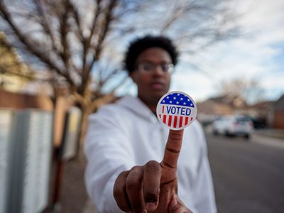 boy holding "i voted" sticker