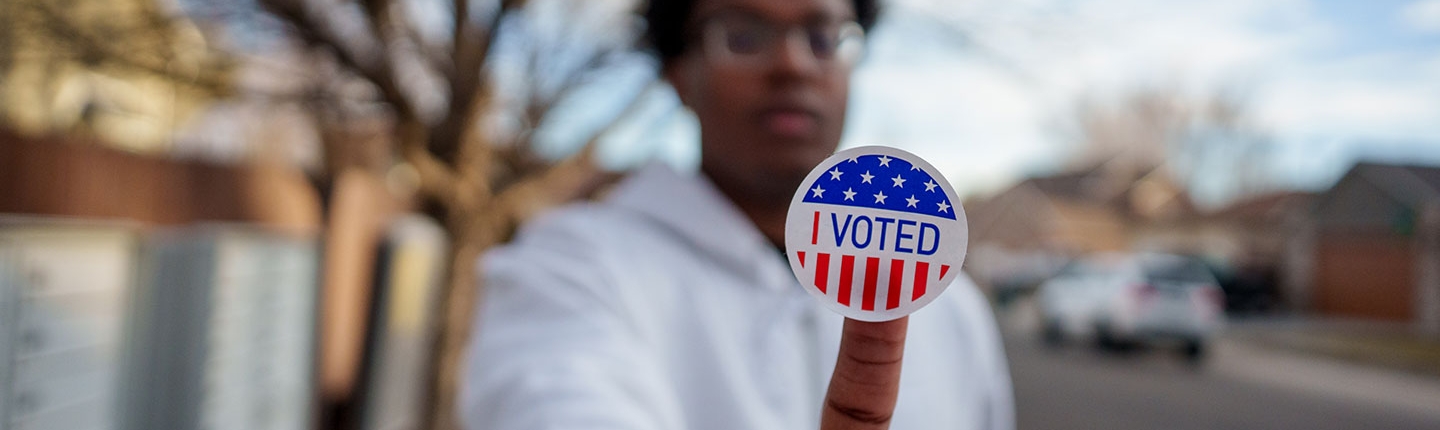 boy holding "i voted" sticker