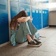 Girl sitting in the school hallway against the lockers with her head on her knees