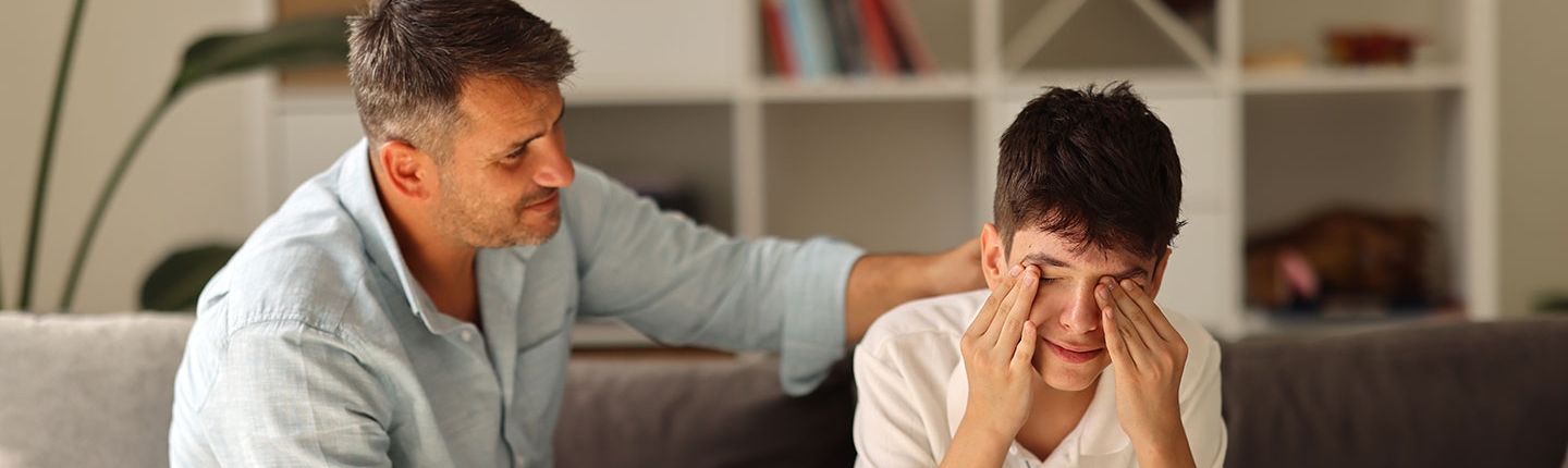 father comforting crying son