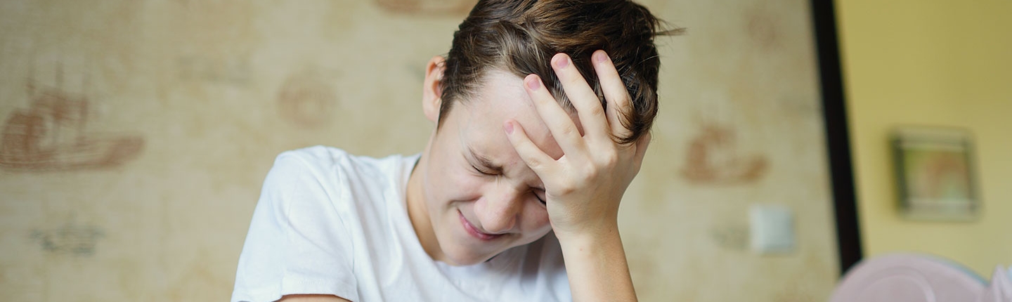 Young boy holding his head