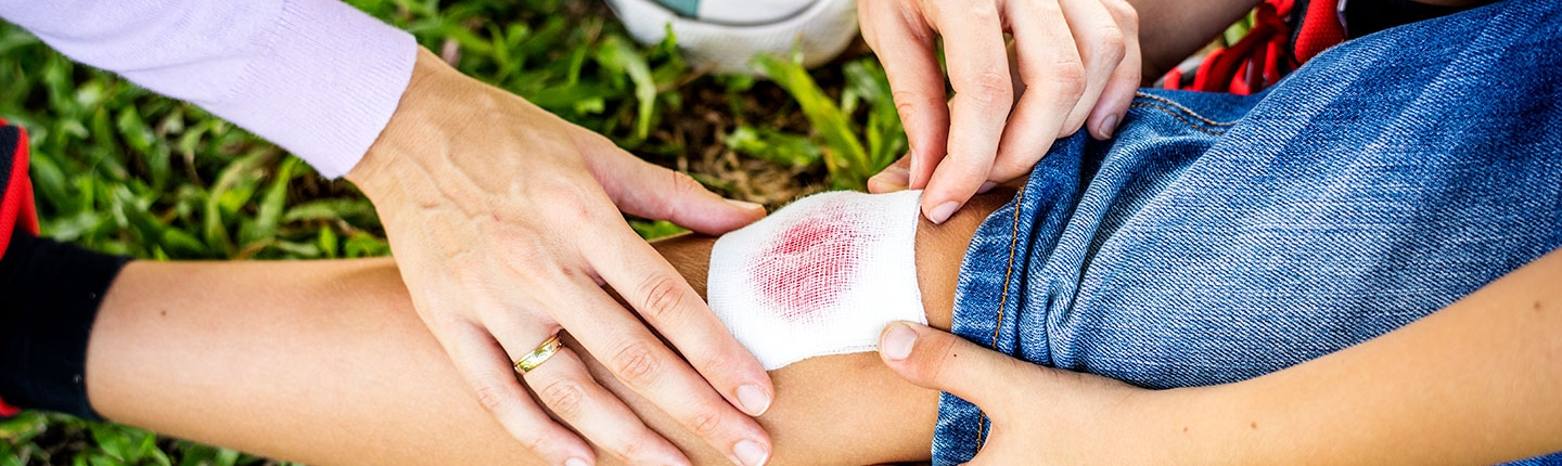 mom doing first aid on child's leg