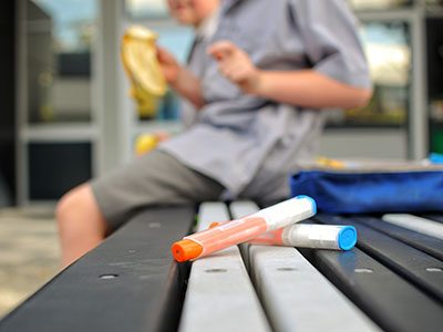 Epi-pen sitting on a bench with a kid in the background