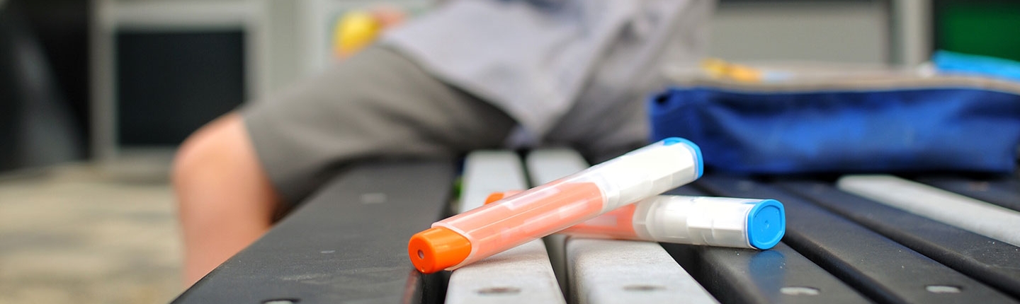 Epi-pen sitting on a bench with a kid in the background