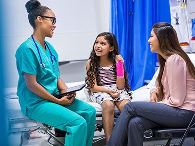 Little girl with arm cast talking to a doctor