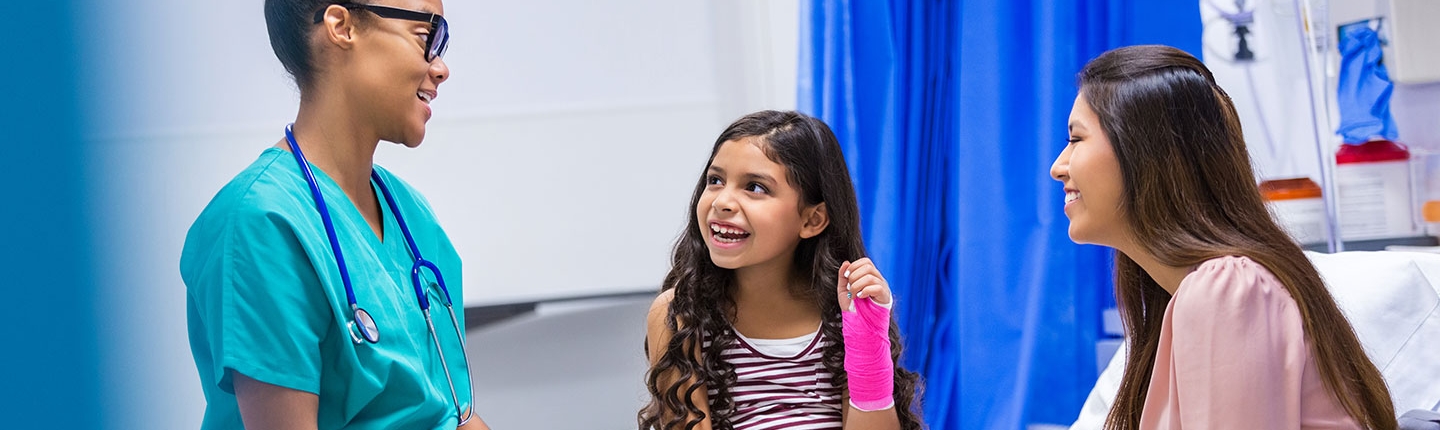 Little girl with arm cast talking to a doctor