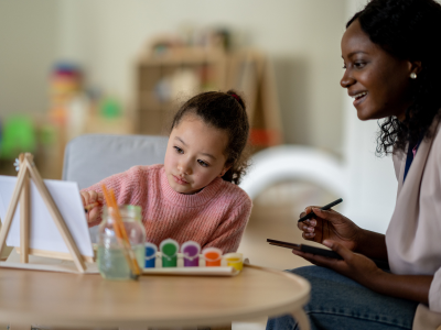 young girl painting with an adult woman