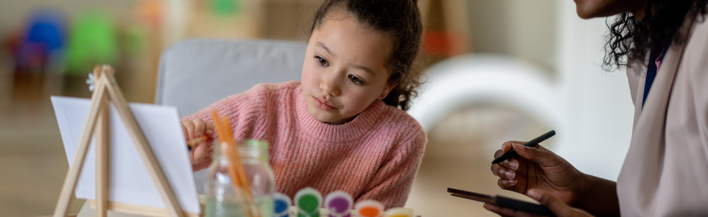 young girl painting with an adult woman