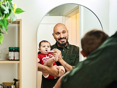 dad brushing baby's teeth