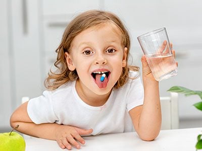 little girl swallowing a pill
