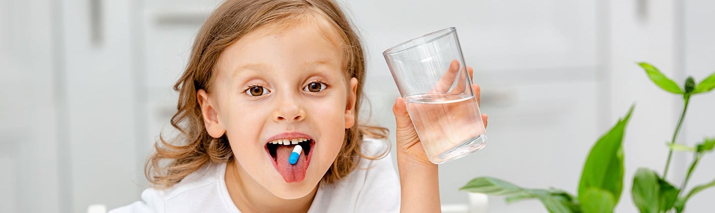 little girl swallowing a pill